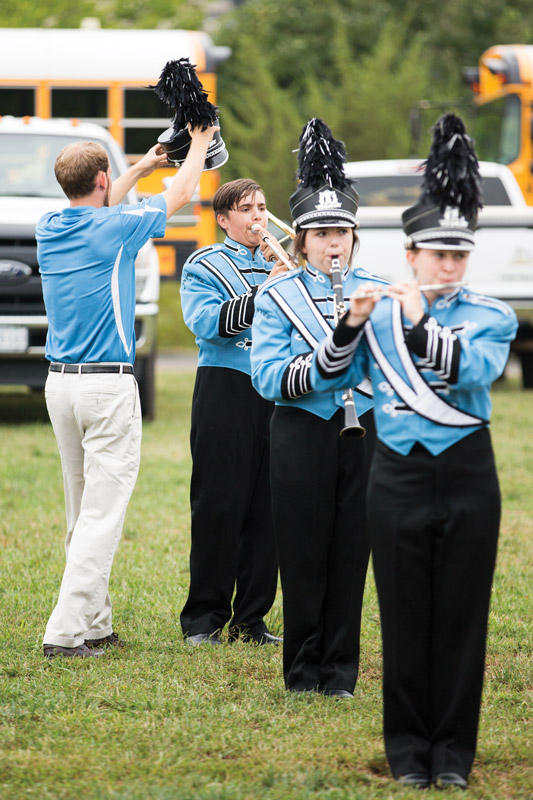 Adam Roach ’04, band director at Eastern View High School in Culpeper County, was busy before the second football game in September. He had to repair the shako of freshman trombonist Everest Head, who was rehearsing with sophomore clarinetist Madison Tate (center) and senior piccolo player Daphne Sink.